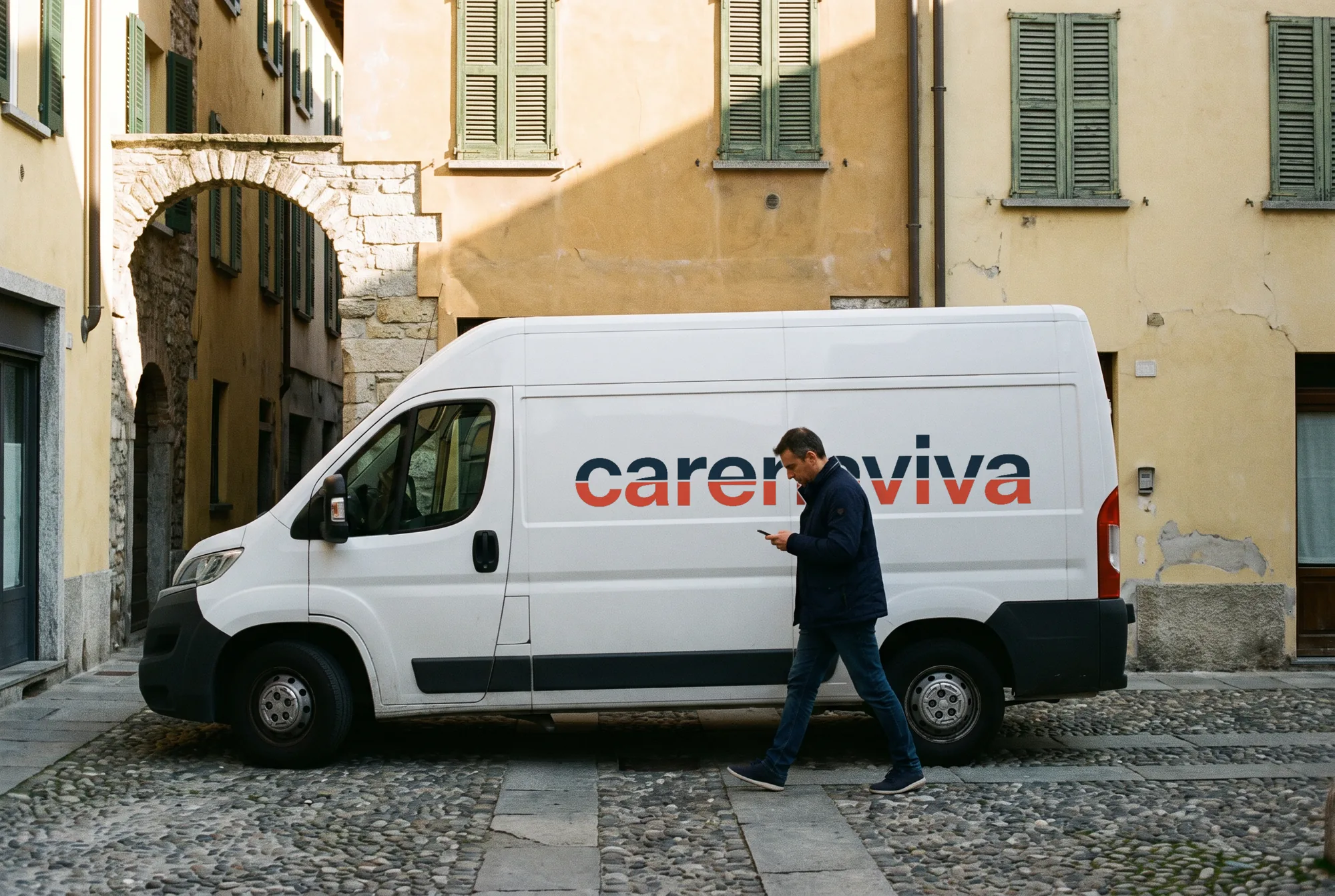 Furgone bianco di consegna con il logo carenaviva in una via di Como